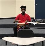 Middle school student playing drums with sticks 